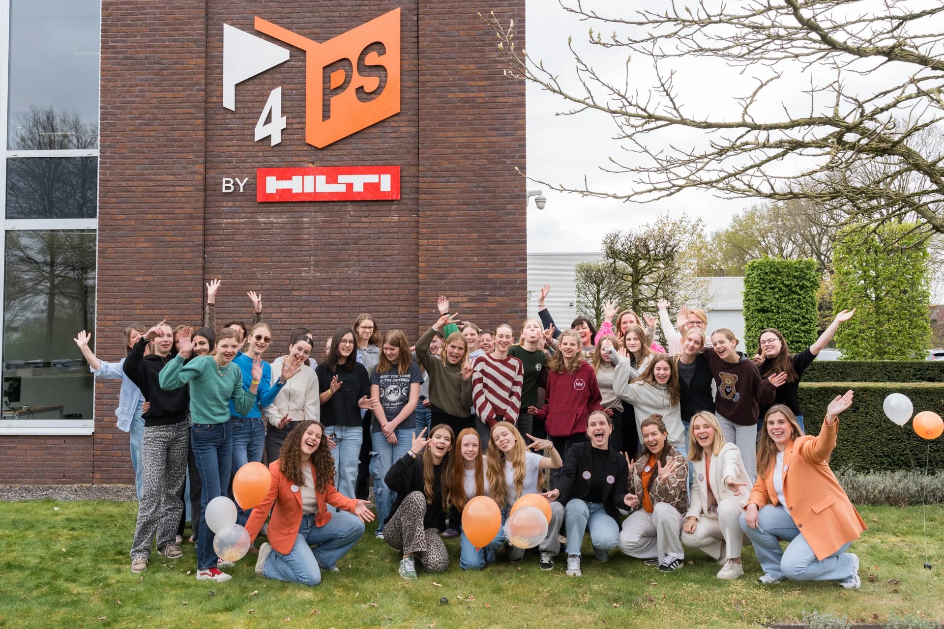 Groepsfoto van deelnemende meiden en medewerkers voor het pand van 4PS