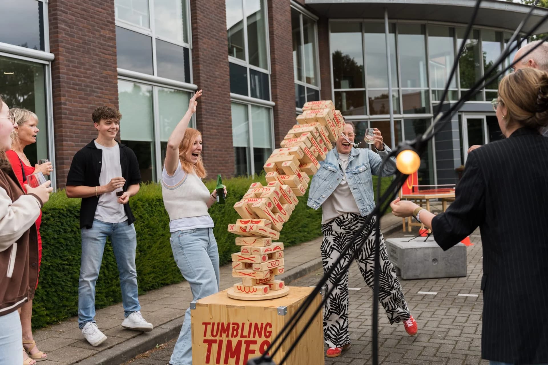 Gasten spelen een groot houten blokkenspel tijdens het zomerfeest van 4PS in 2024.