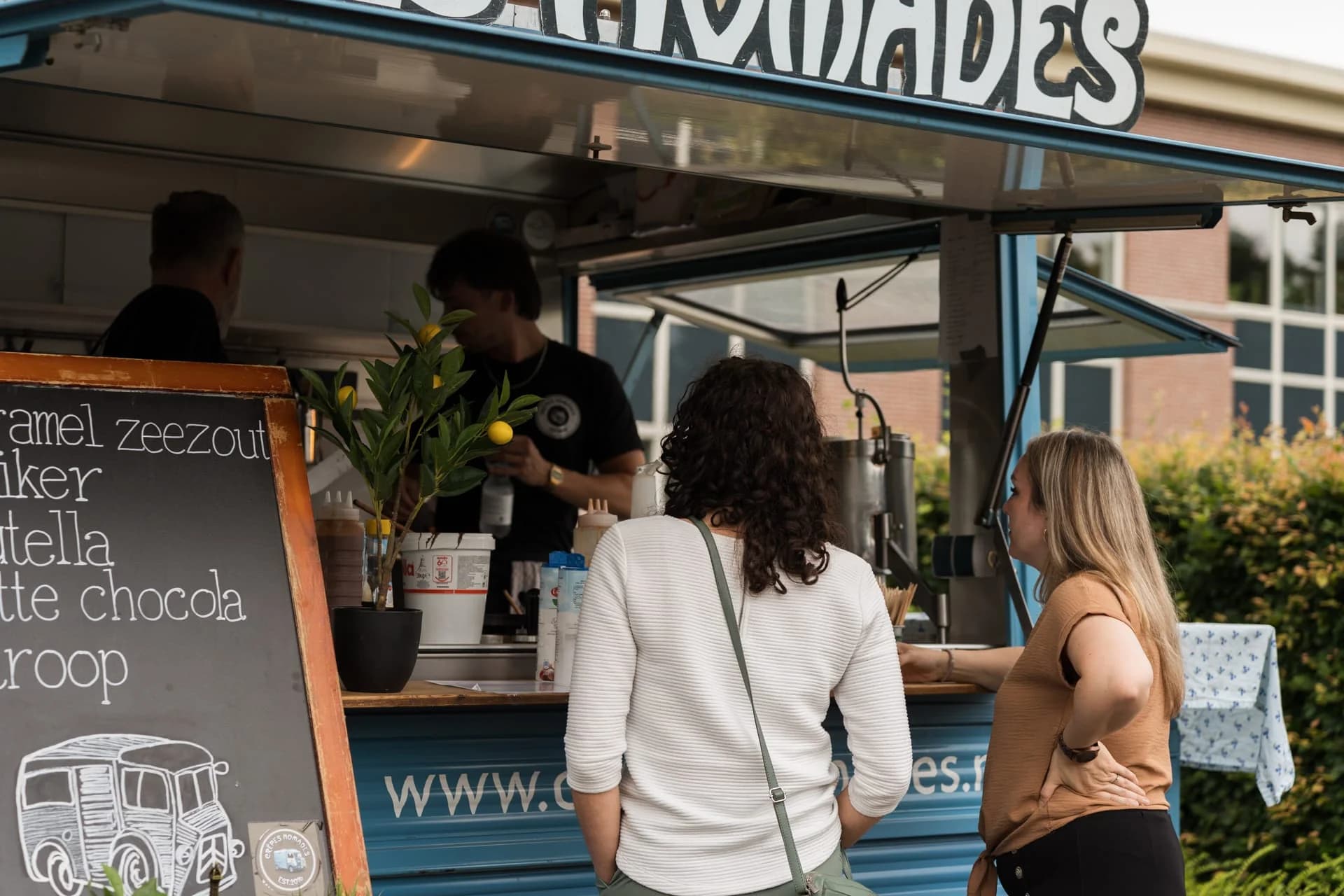 Gasten bestellen eten bij een foodtruck tijdens het zomerfeest van 4PS.