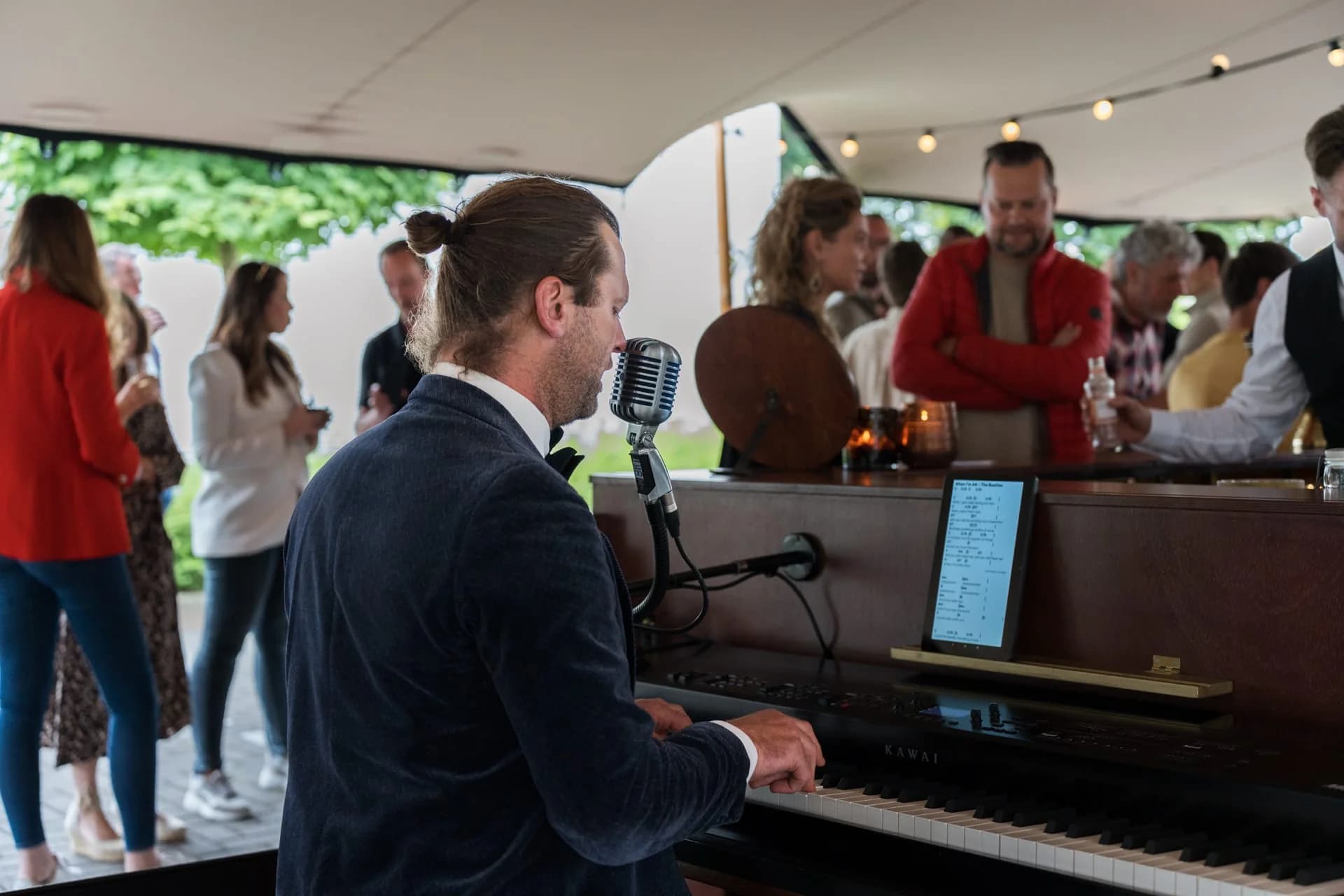 Pianist speelt voor gasten in de feesttent tijdens het zomerfeest van 4PS.