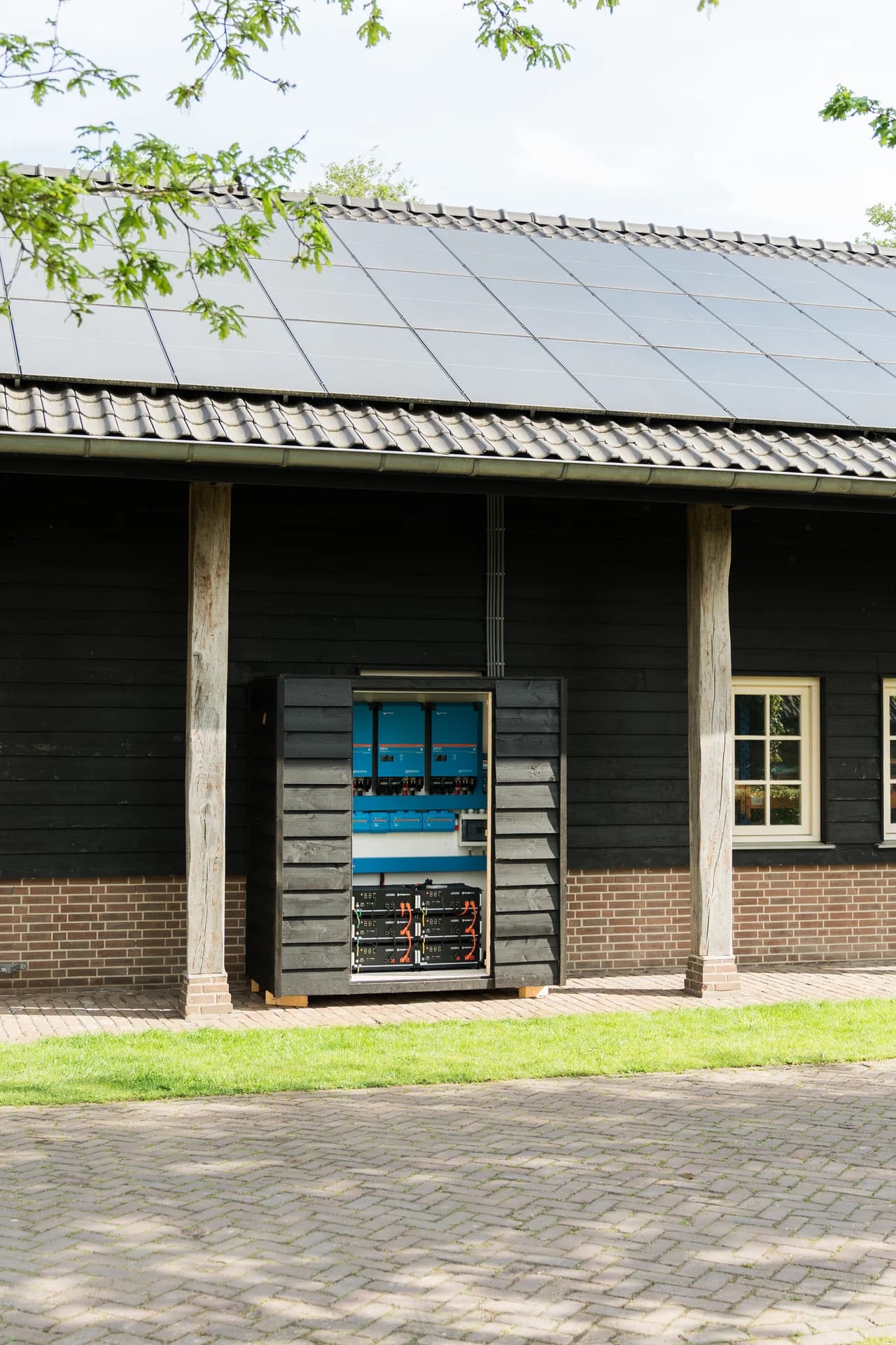 Geopend accusysteem onder de zonnepanelen van een houten schuur.