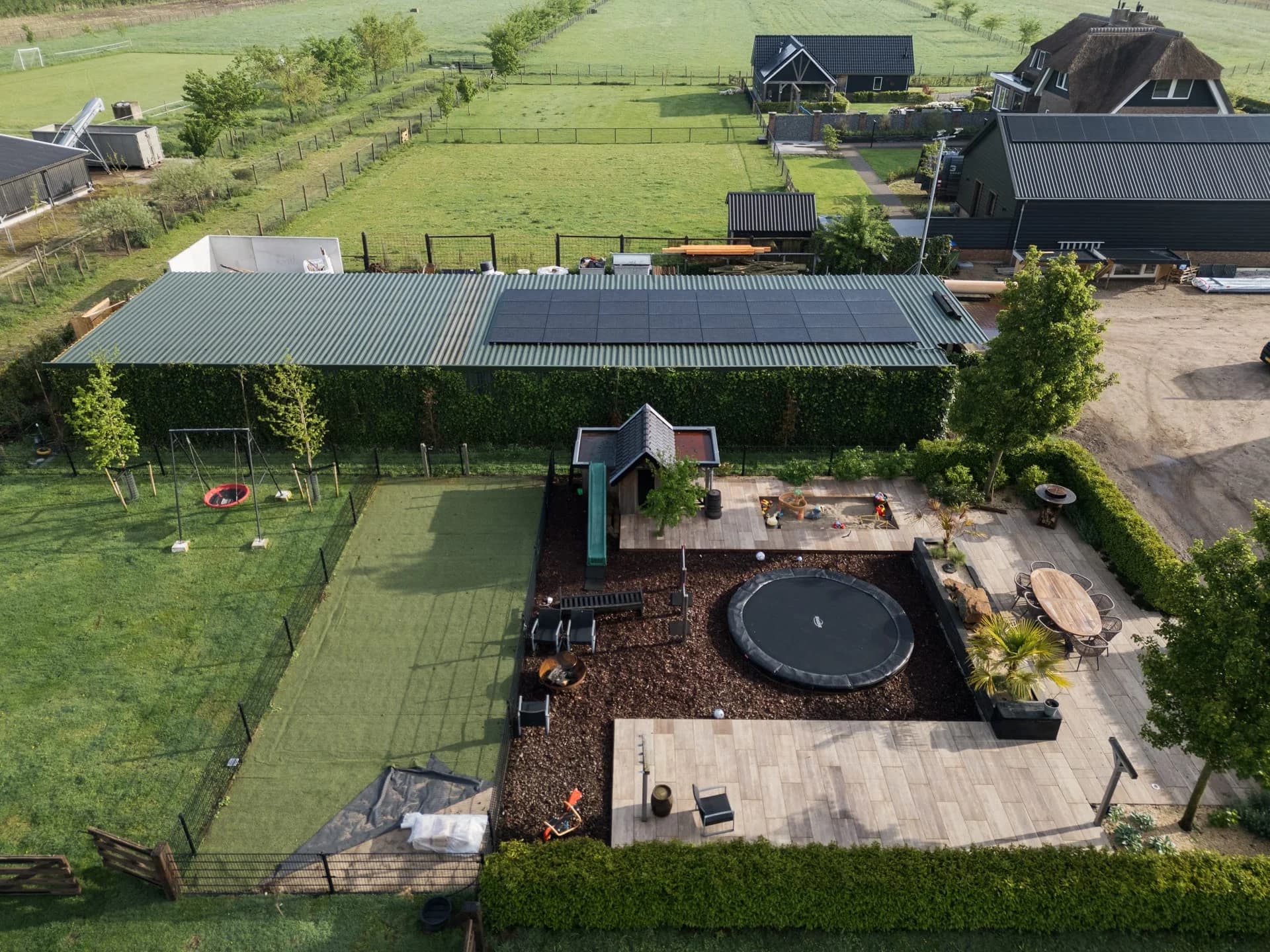 Luchtfoto van zonnepanelen op een schuurdak naast een woonerf.
