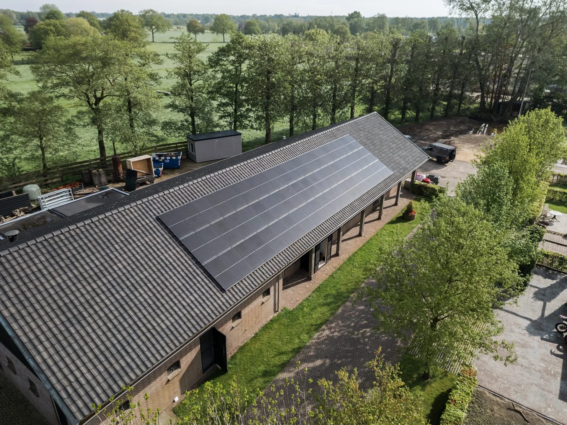 Luchtfoto van zonnepanelen op het pannendak van een schuur.
