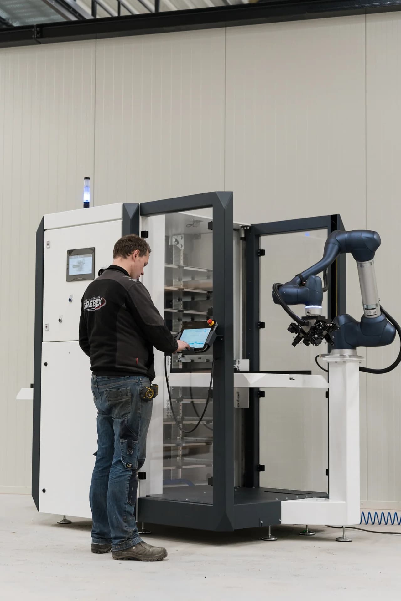 Medewerker bedient de MetaLoader van Grebex naast de robotarm.