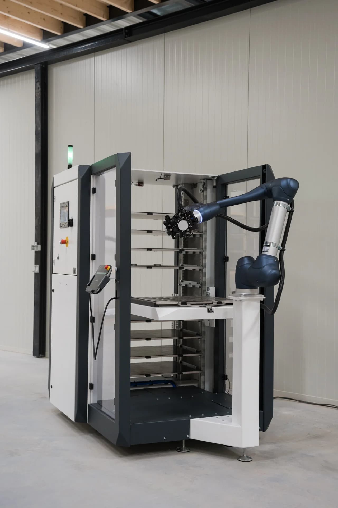 MetaLoader met robotarm en platenmagazijn in een werkplaats.