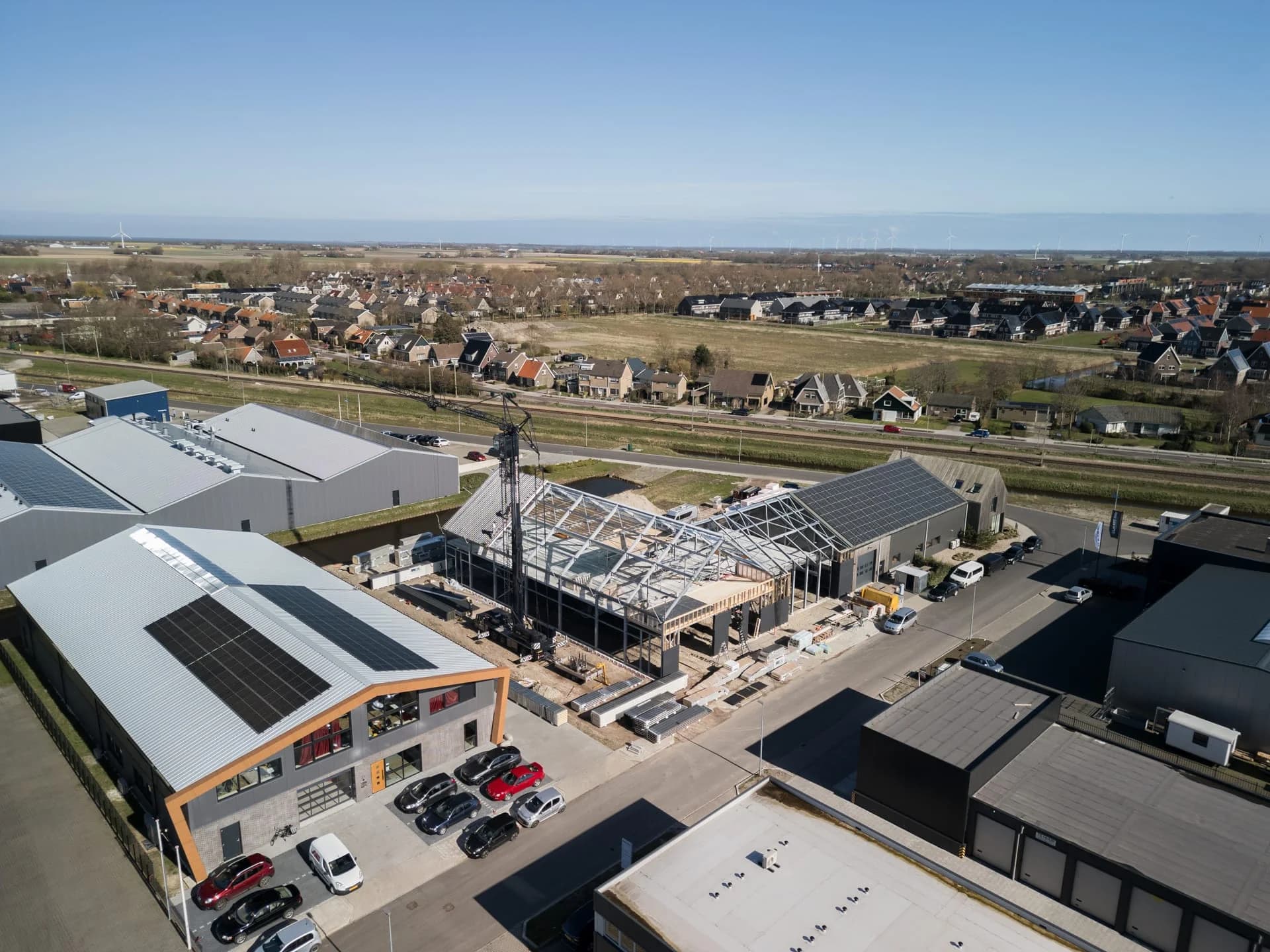 Luchtfoto van bedrijfshallen en een hal in aanbouw voor Middendorp Montage.
