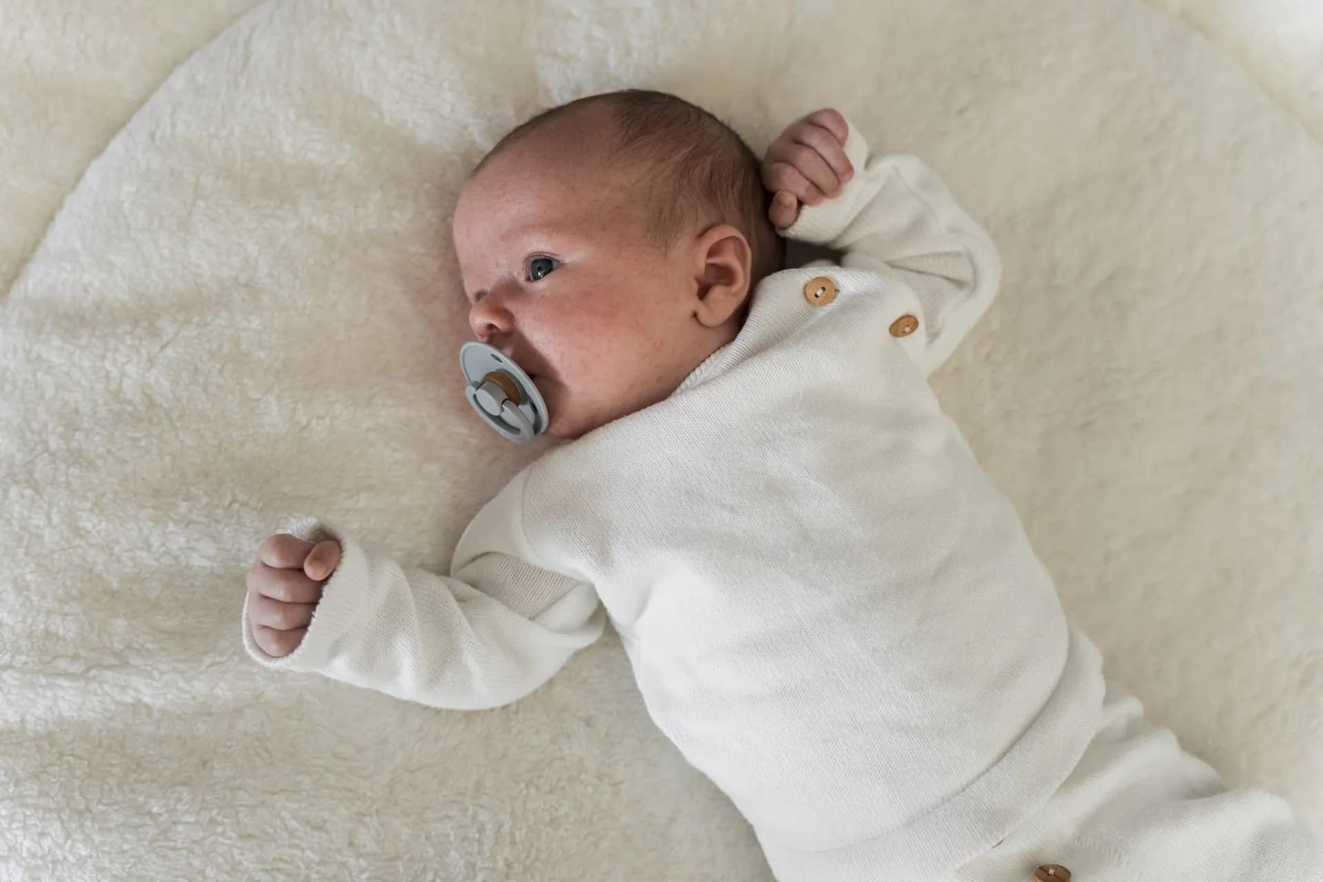 Baby Juda ligt met een speen op een lichte deken