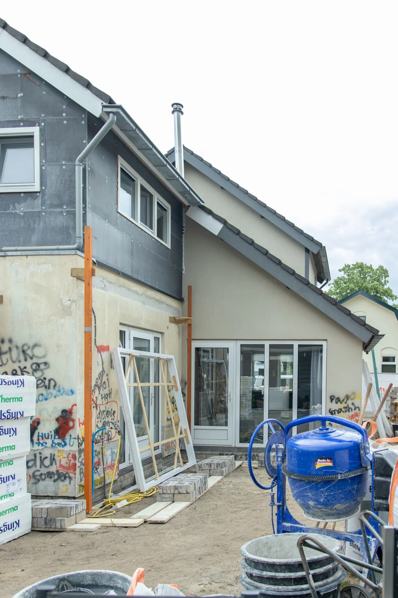 Gevel van een woning tijdens de renovatie met kozijnen en bouwmateriaal.