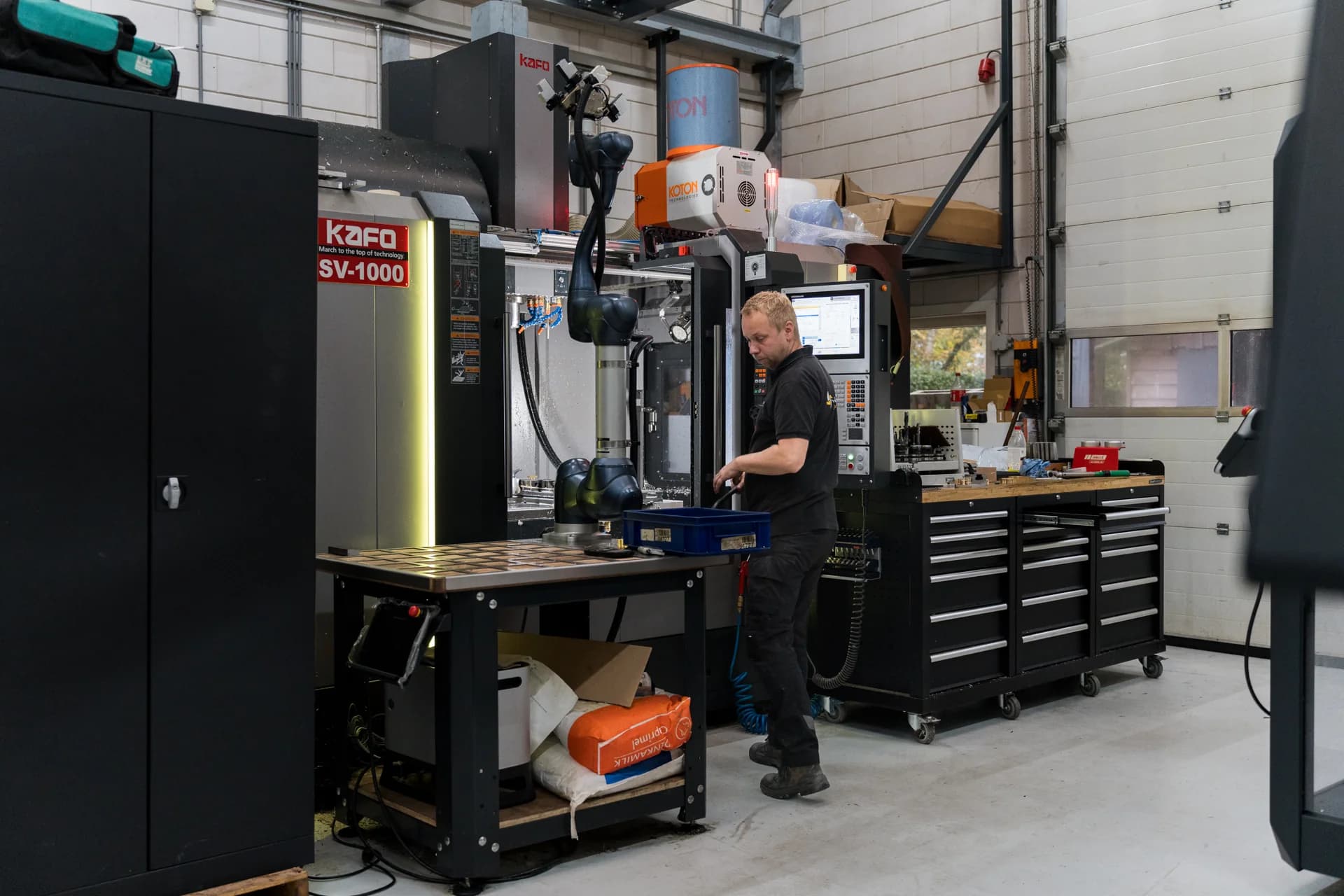 Medewerker werkt naast een robotarm en CNC-machine in de werkplaats.