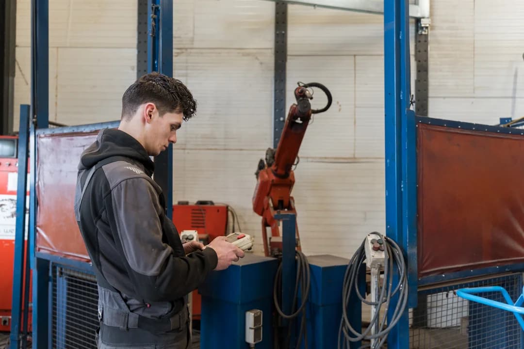 Medewerker bedient een robotinstallatie voor metaalbewerking.