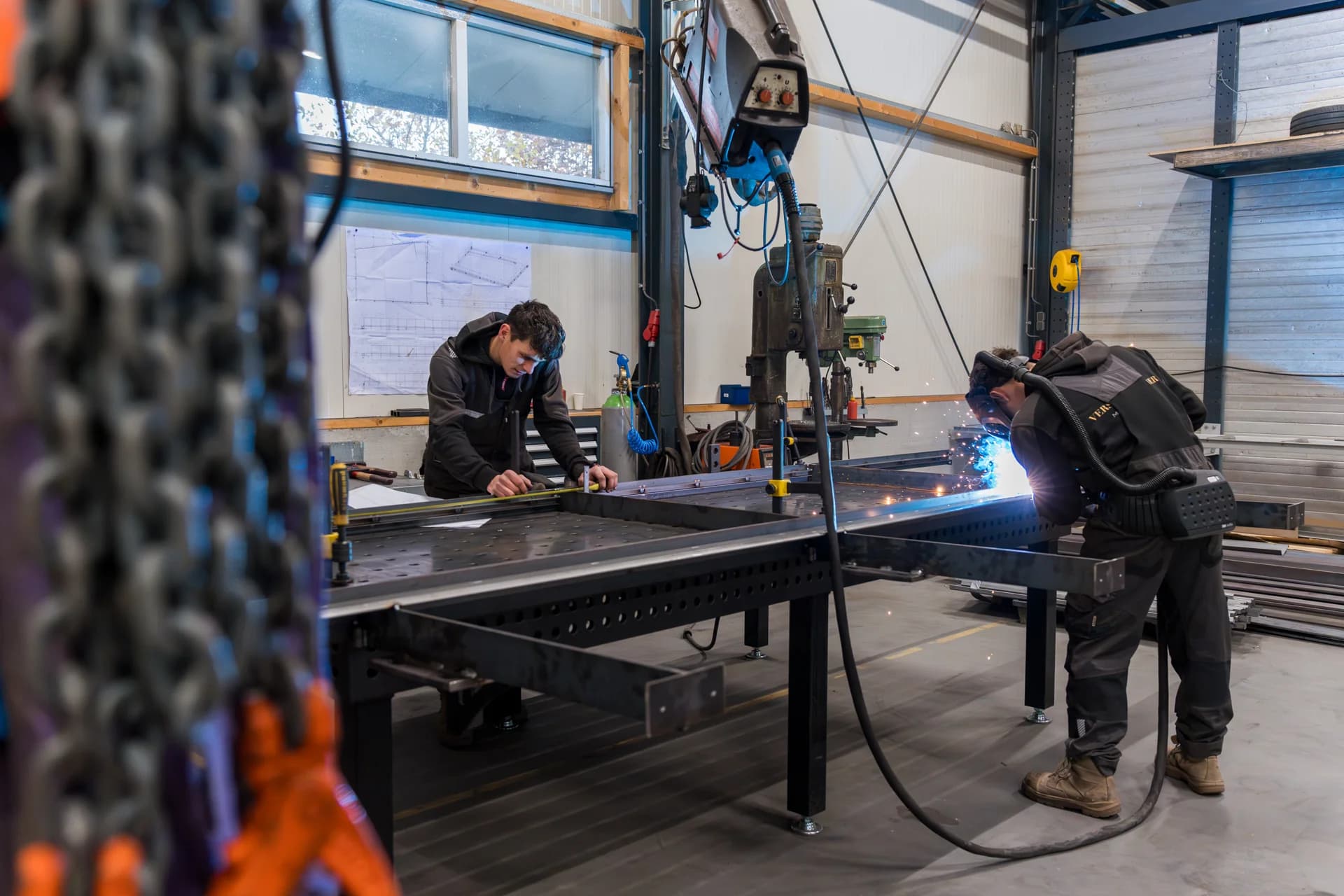 Medewerkers lassen en werken aan metalen onderdelen in de werkplaats.
