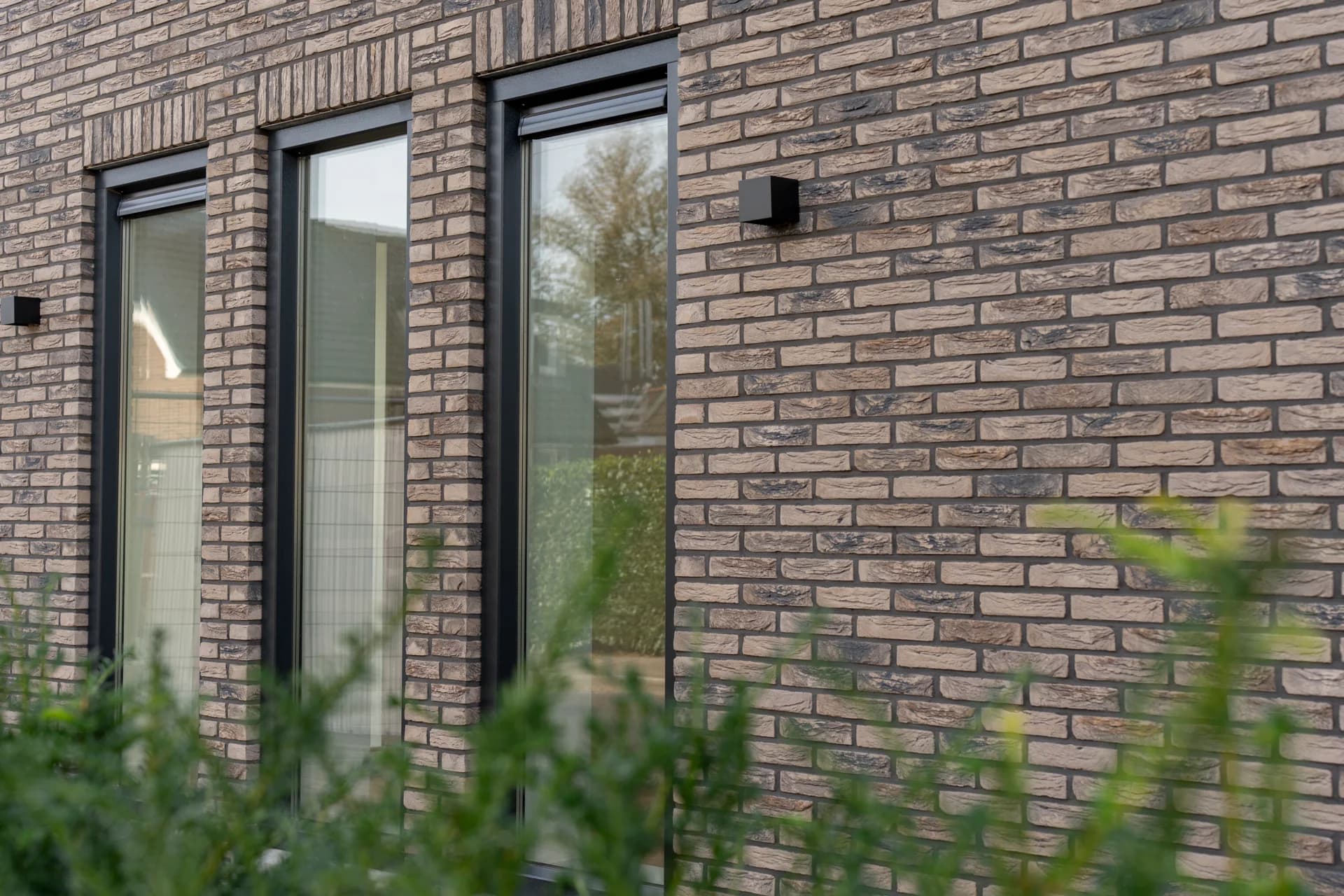 Nieuwe bakstenen gevel met hoge ramen na de renovatie.