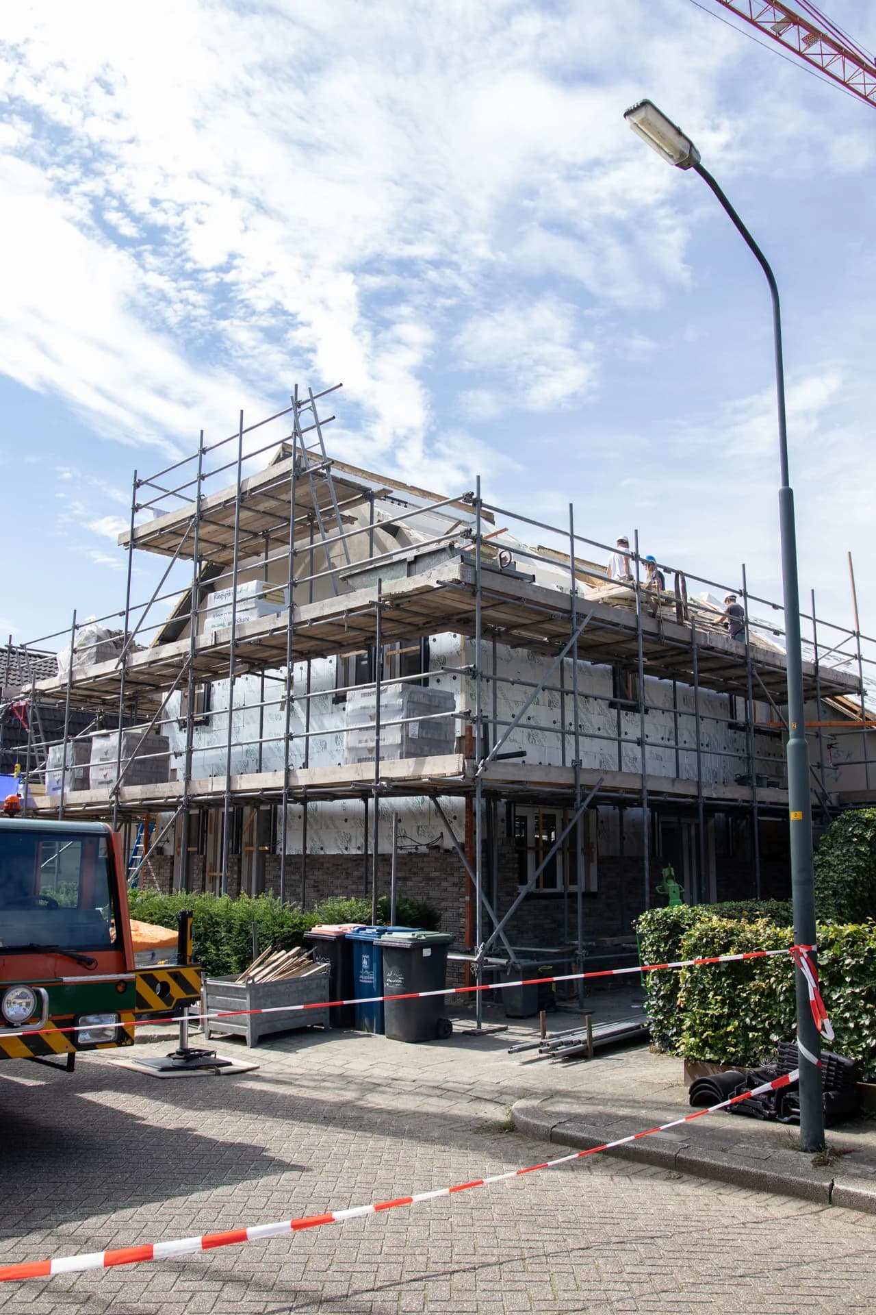 Woning in renovatie met steigers en medewerkers op het dak.